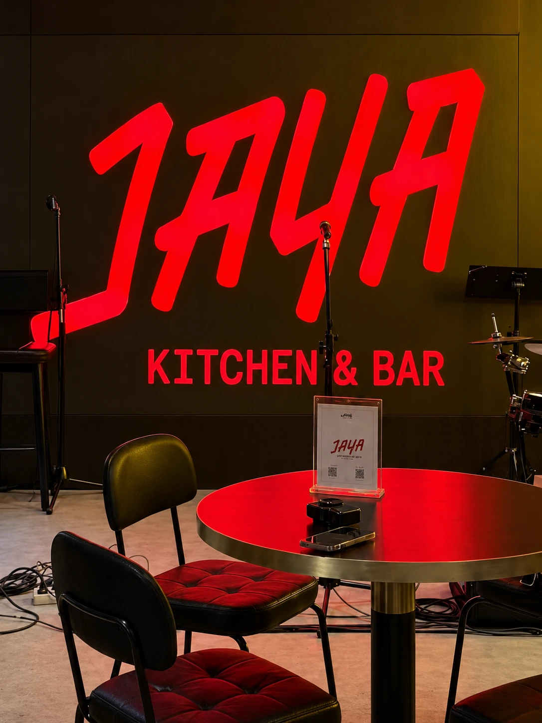 Jaya’s red stage sign above a table and live music equipment